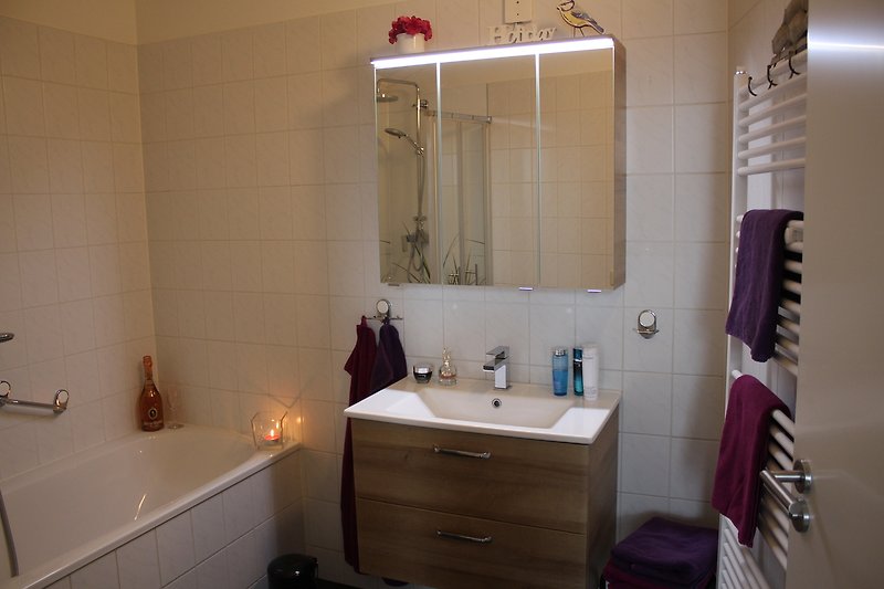 Modernes Badezimmer mit Lichtspiegel, Waschtisch, Unterbauschrank und Röhrenheizkörper