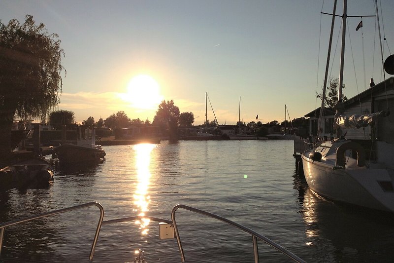 Abendstimmung am Wasser mit Boot und Sonnenuntergang.