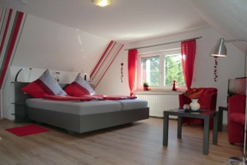 Das rote Schlafzimmer mit nett gestaltetem Ambiente, Sitzecke und TV