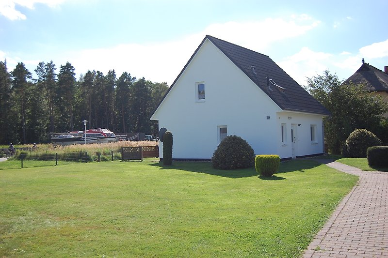 Ländliches Anwesen mit Garten, Bäumen und einer Kirche im Hintergrund.