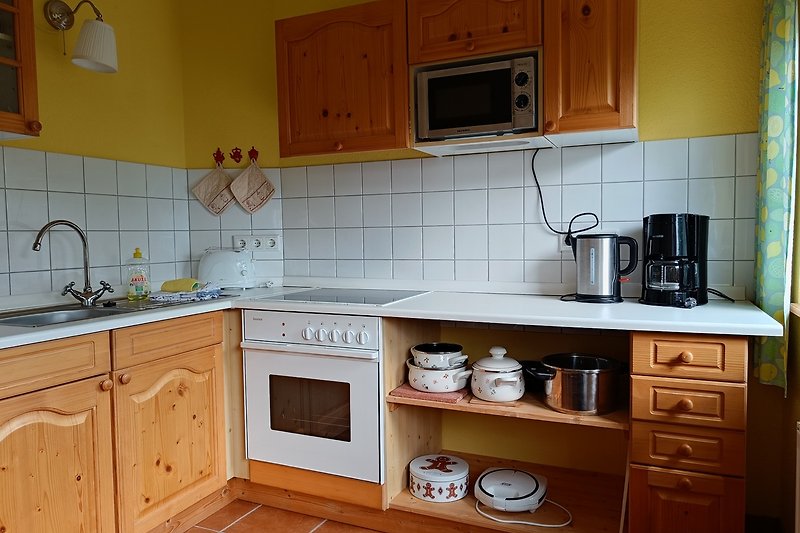 Moderne Küche mit Holzboden, Schränken und Küchengeräten.