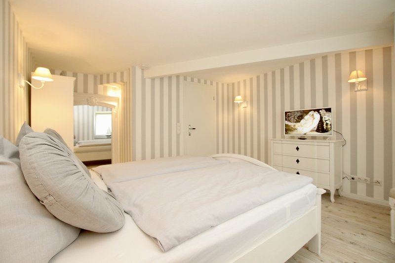 Stilvolles Schlafzimmer mit Doppelbett und TV