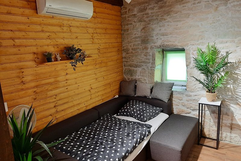 Gemütliches Wohnzimmer mit Pflanzen, Holzmöbeln und Fensterblick.