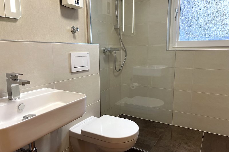 Ein modernes Badezimmer mit Spiegel, Waschbecken und Dusche.