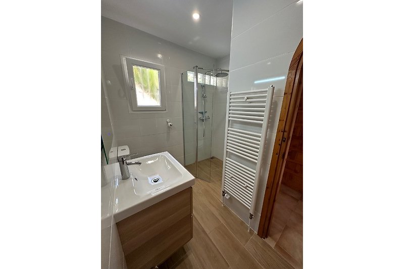 Moderne Badezimmergestaltung mit Holzboden und Fenster.