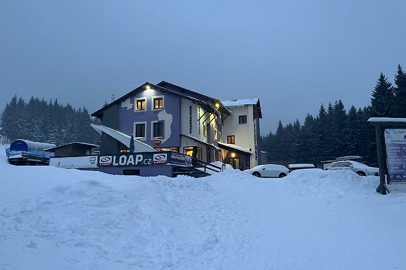 Schneebedeckte Berge und ein gemütliches Haus in einer winterlichen Landschaft.