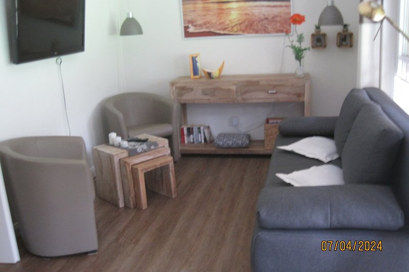 Wohnzimmer mit bequemen Möbeln, Holzboden und Pflanzen.