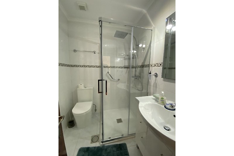 Ein modernes Badezimmer mit Dusche, Waschbecken und Spiegel.