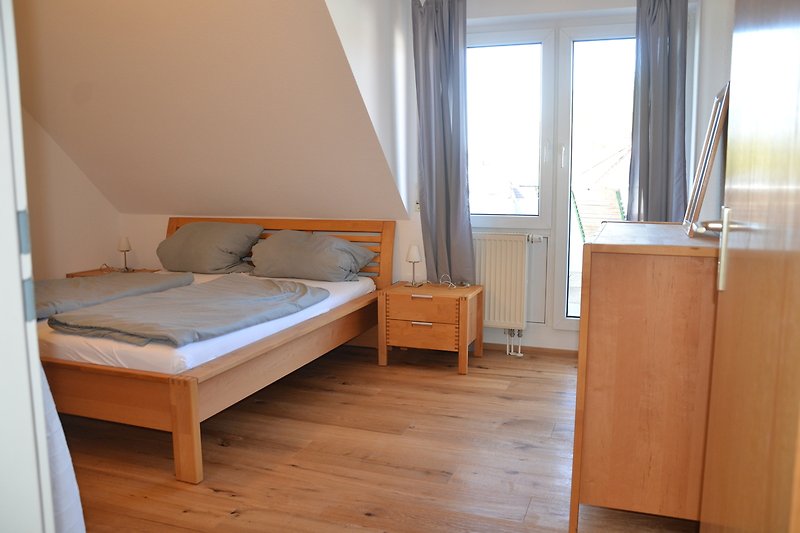 Gemütliches Schlafzimmer mit Holzmöbeln, bequemem Bett und Fenster.