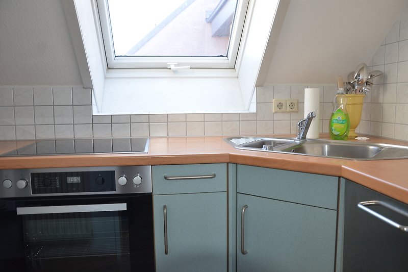 Küche mit Induktion Kochplatten, Arbeitsplatte und Fenster.