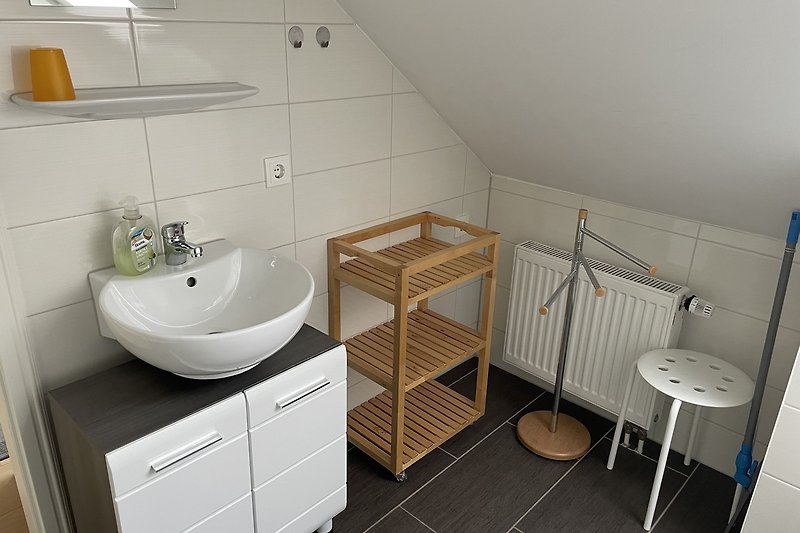 Moderne Badezimmerausstattung mit Waschbecken, Spiegel und Schrank.