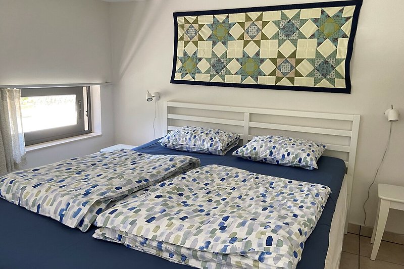 Gemütliches Schlafzimmer mit Holzmöbeln und blauer Bettwäsche.