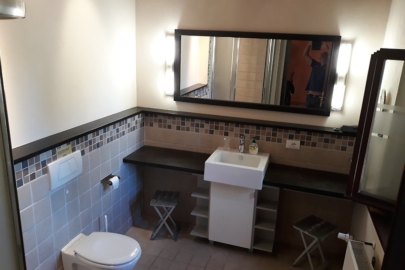 Badezimmer mit "rustico" Design und großem Spiegel.