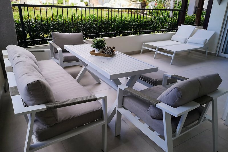 Gemütliche Terrasse mit bequemen Möbeln und Pflanzen.