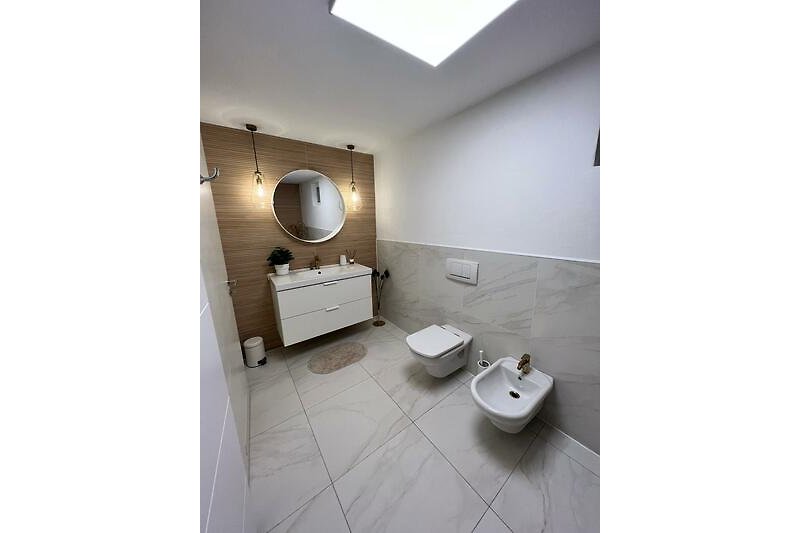 Modernes Badezimmer mit Spiegel, Waschbecken, Toilette und Schrank.