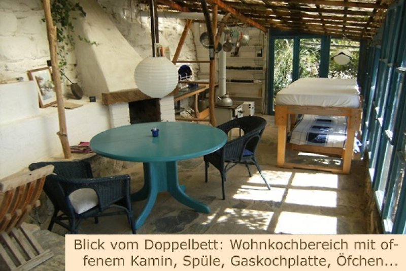 Blick vom Doppelbett: Wohnkochbereich mit off. Kamin, Spüle, Anrichte, Gaskochplatten, Deko-Öfchen