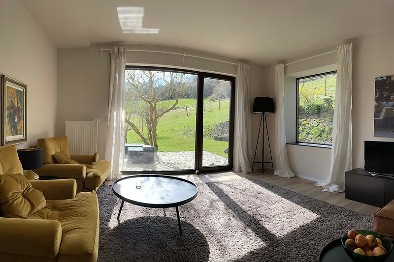 Geräumiges Wohnzimmer mit bequemer Couch, Sesseln und Panoramablick.