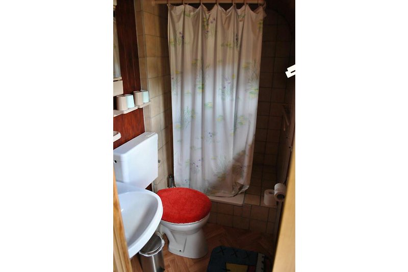 Schönes Badezimmer mit Duschvorhang, Fenster und Holzboden.