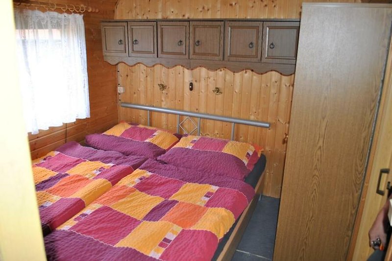 Gemütliches Schlafzimmer mit Holzmöbeln und gemusterten Vorhängen.