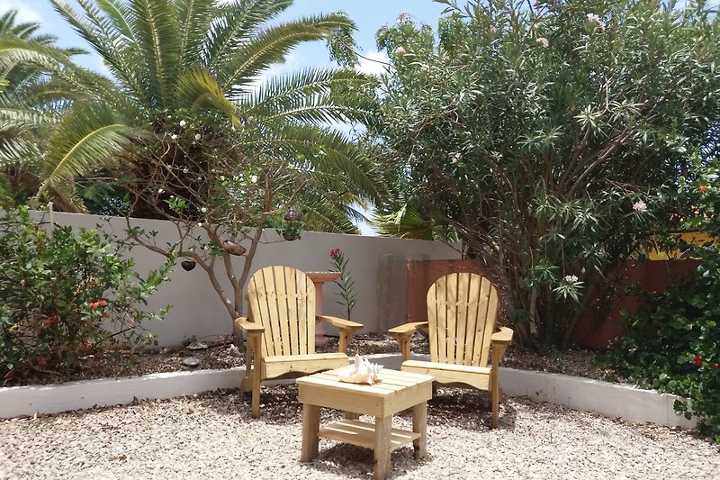 Tropischer Garten mit Palmen, Outdoor-Möbeln und grüner Landschaft.