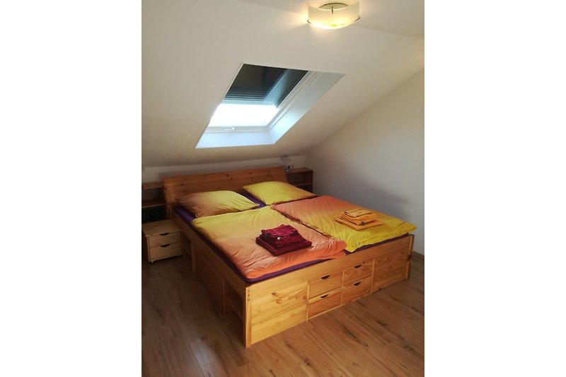 Gemütliches Schlafzimmer mit erhöhtem Bett und zusätzlichem Stauraum - hier (optional) mit Bw + Handtüchern