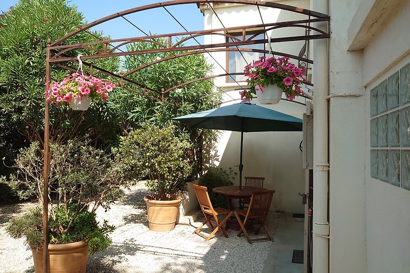 Blühender Garten mit bunten Blumen, gemütlicher Sitzbereich und Sonnenschutz.