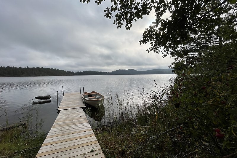 Ein ruhiger See umgeben von Natur und einem Boot.
