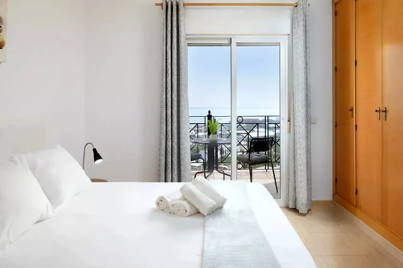 Meerblick vom Balkon mit Pool, Outdoor-Möbeln und komfortablem Bett.