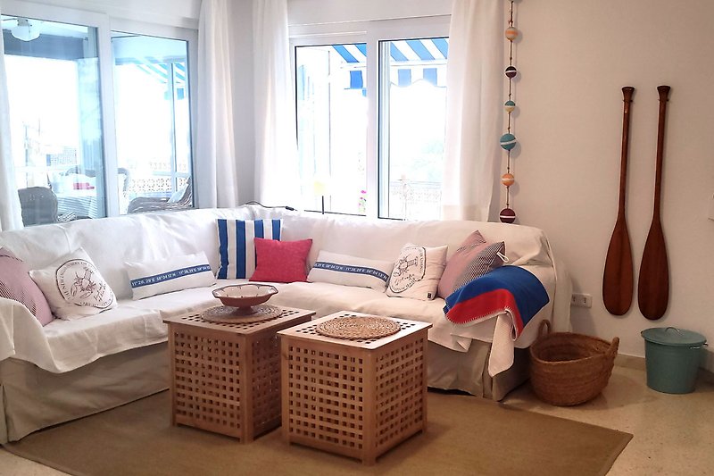 das gemütliche Wohnzimmer mit bequemer Couch ist liebevoll im maritimen Stil eingerichtet