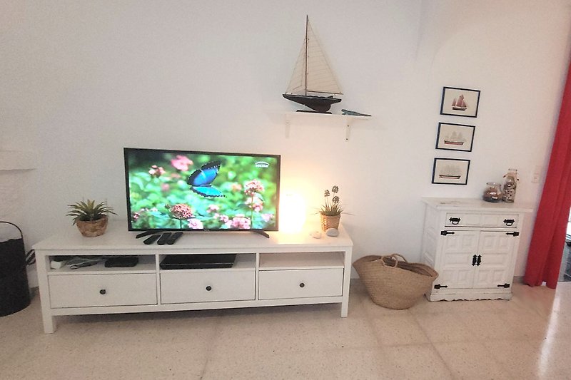Modernes Wohnzimmer mit Unterhaltungszentrum, Fernseher, Pflanze und Regalen.