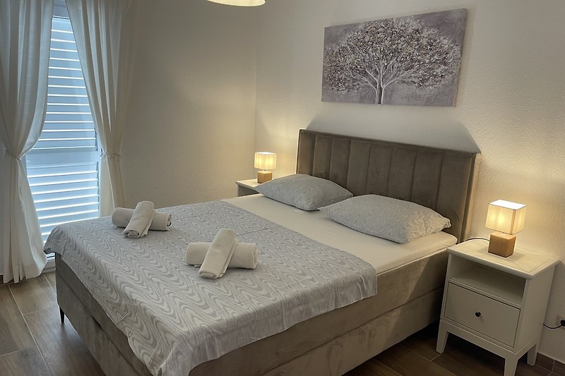 Stilvolles Schlafzimmer mit Holzmöbeln und grauem Bettzeug.