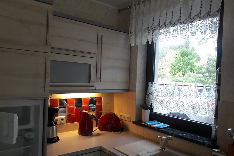Moderne Küche mit Holzregalen, Küchengeräten und Fensterblick.