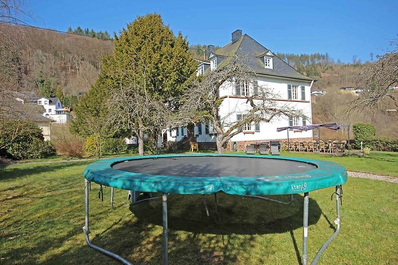 Ferienhaus mit Trampoline und Sportausrüstung in idyllischer Umgebung.