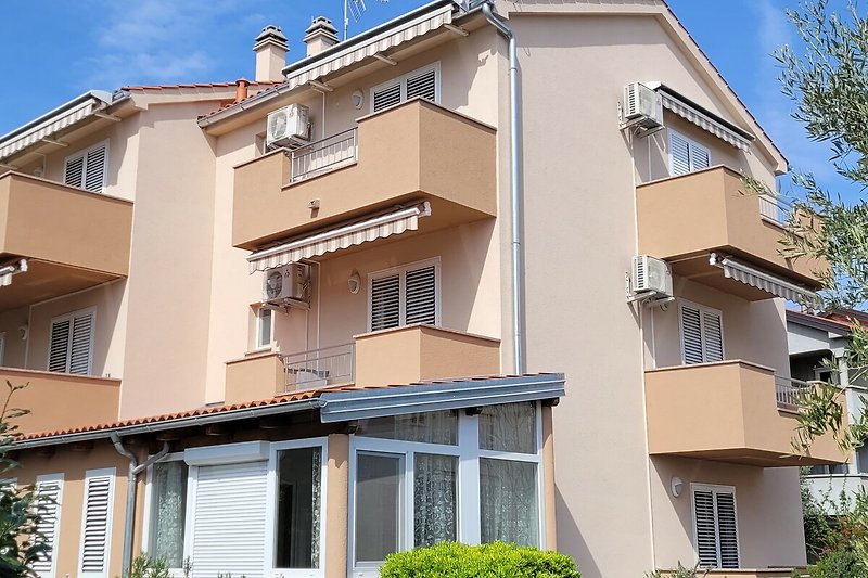 Casa moderna con balcone, facciata in legno e ambiente verde.