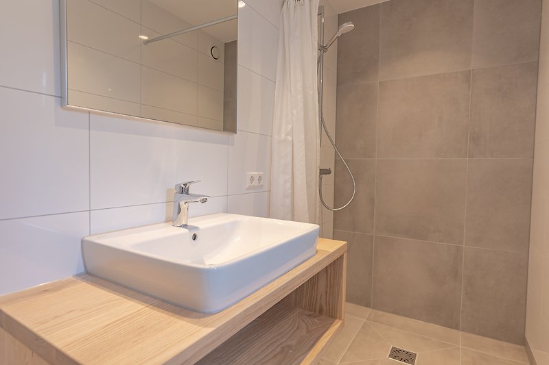 Moderne badkamer met stijlvolle tegelvloer en glazen douchewand.