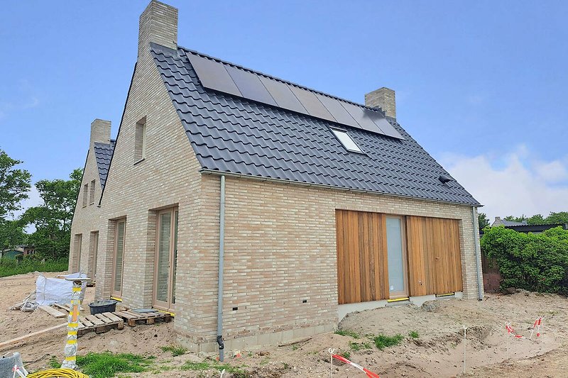 Ziegelhaus mit Schornstein und Einfahrt, umgeben von Natur.