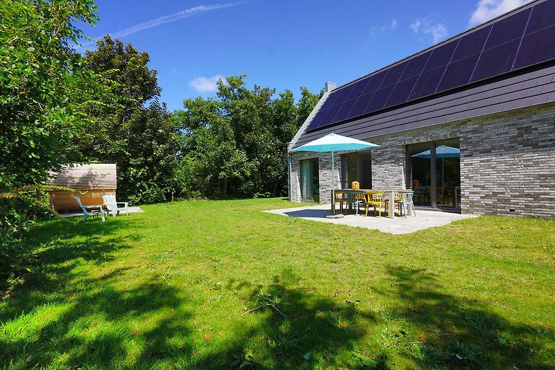 Energieeffizientes Haus mit Solarpanelen und gepflegtem Garten.