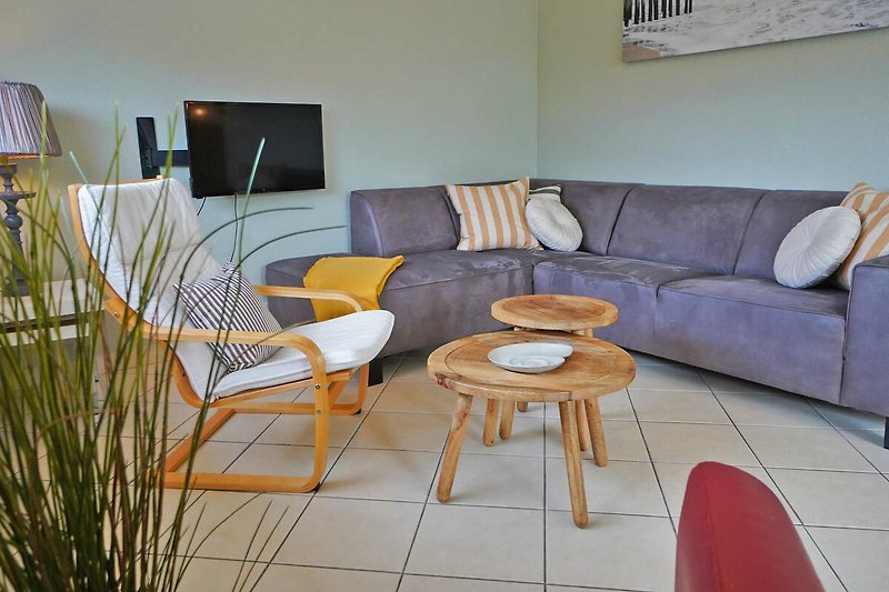 Modernes Wohnzimmer mit bequemer Couch, Tisch, Pflanzen und Kunst.