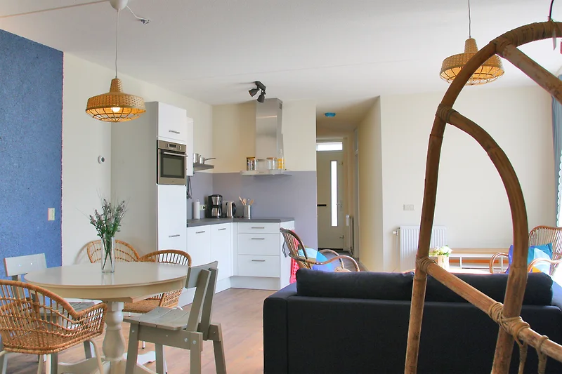 Offener Wohnraum mit Sessel, Tagesbett, Couchtisch und TV-Anrichte.