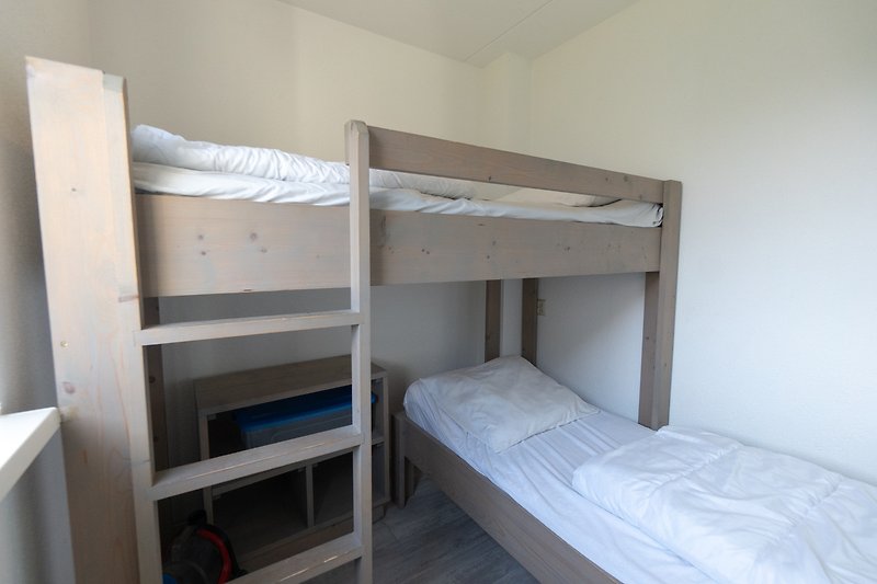 Dormitory mit Etagenbett, Regal, Bettwäsche und Leiter.