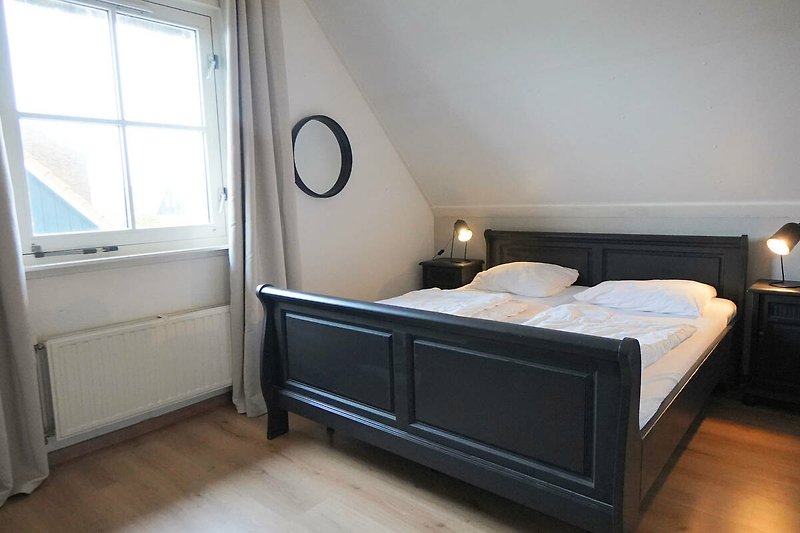 Stilvolles Schlafzimmer mit Holzmöbeln, gemütlichem Bett und elegantem Licht.