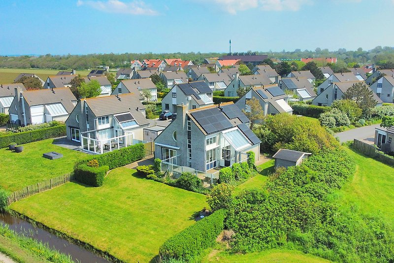 Blick auf grünes Land mit Haus, Bäumen und Hügeln im Hintergrund.