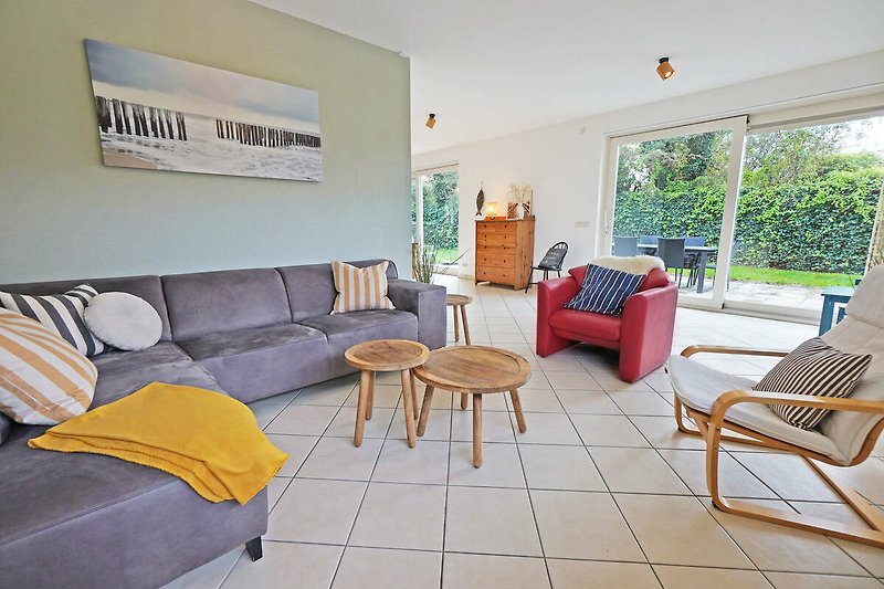 Stilvolles Wohnzimmer mit bequemer Couch, Tisch, Pflanzen und Fenster.