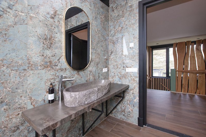 Stilvolles Badezimmer mit elegantem Spiegel, modernen Armaturen und Holzboden.