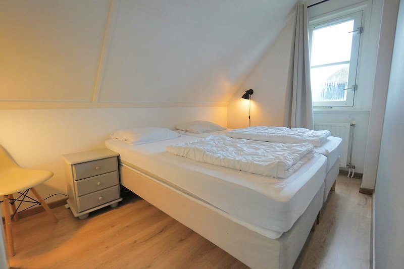Schlafzimmer mit gemütlichem Bett, Fenster und stilvoller Beleuchtung.
