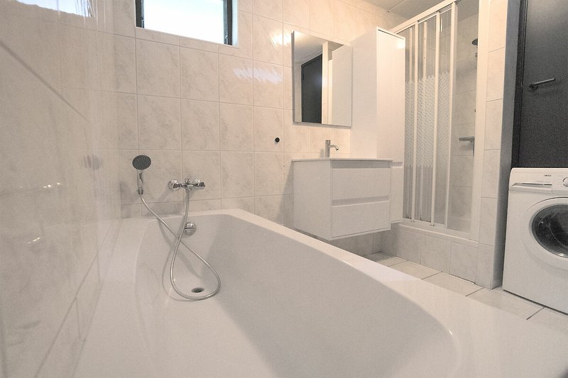 Luxuriöses Badezimmer mit Badewanne, Dusche und Fenster.