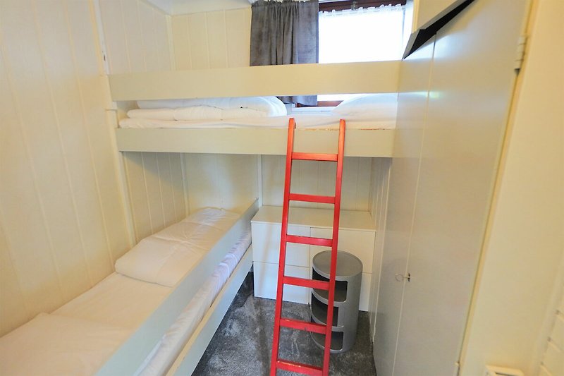 Ein gemütliches Zimmer mit Etagenbett, Leiter und Regal.
