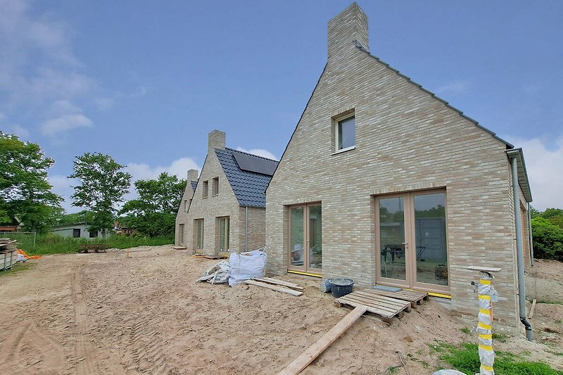 Gemütliches Landhaus mit rotem Dach und breitem Schornstein.