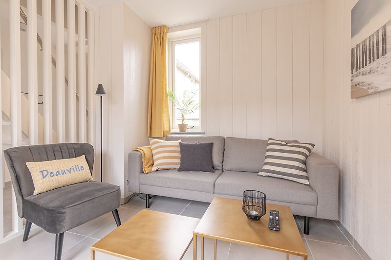 Comfortabele woonkamer met houten meubels en grote ramen.