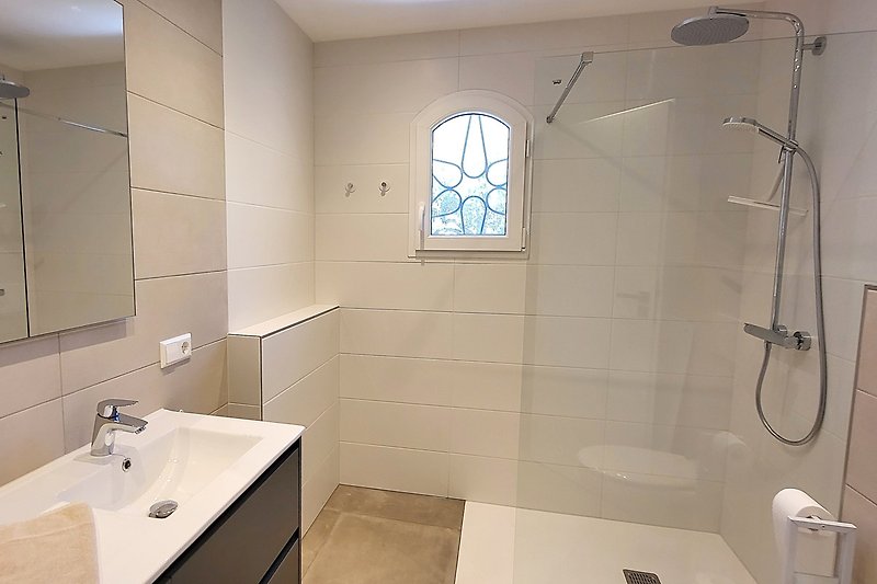 Modernes Badezimmer mit Dusche, Waschbecken, Spiegel und Fenster.